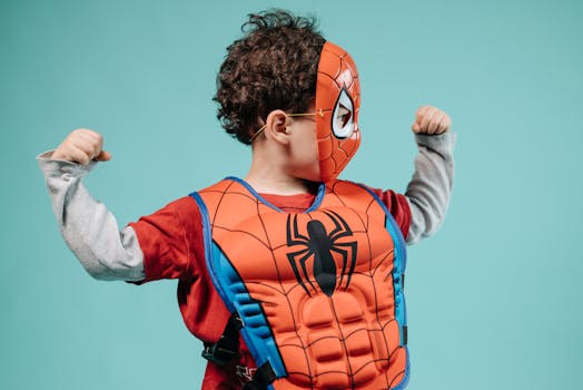 Young child posing in Spider-Man costume with turquoise background showcasing imagination.